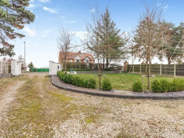 The last photo in our gallery shows the front garden. By the driveway, it is laid to lawn with low, brick-walled boundaries, raised beds, slate chippings and trees.