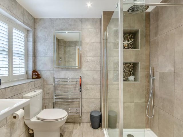 A second stylish en suite at Holly End, with a walk-in, tiled shower enclosure featuring two recess areas. There is also a wall-hung wash hand basin, low-flush WC, chrome, heated towel-rail, fitted mirror with inset touch-screen LED lighting, five ceiling spotlights and tiled floor and walls.