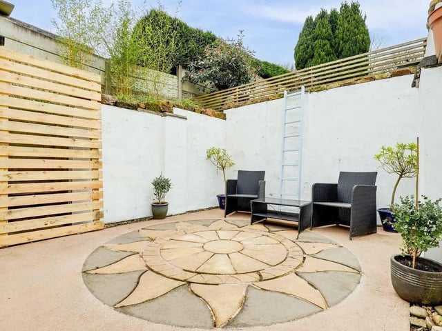 The garden boasts a decorative stone seating area and a pergola with wisteria plants. The perfect place to enjoy a morning coffee.