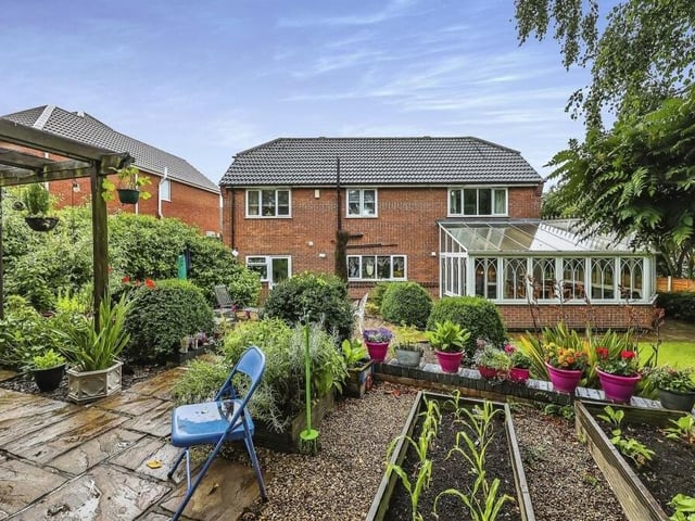 Let's step outside now and take a view of the back of the house, including the commanding conservatory to the right. A snap shot of the rear garden shows how busy it is, with shrubs, bushes, plants and trees and a feature pergola to the left.