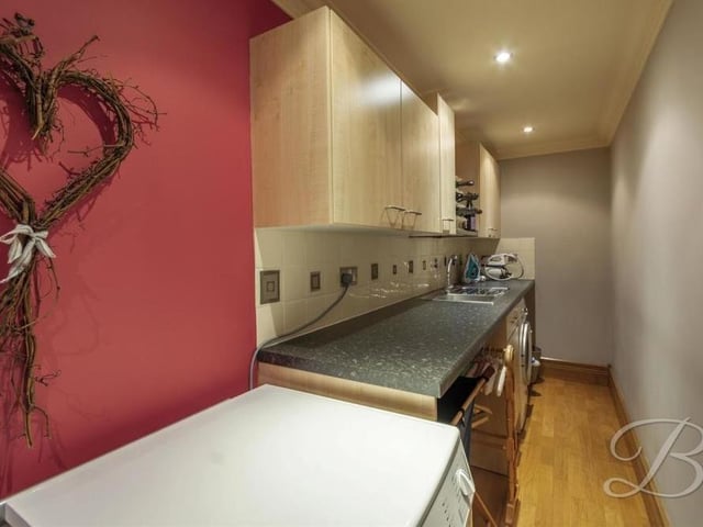 The downstairs level of the Chesterfield Road bungalow also houses this handy utility room, complete with wooden flooring and downlights. There is space and plumbing for a tumble dryer.