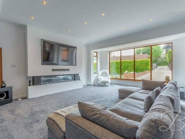 The sitting room is bright and cosy, with fitted carpets,, an electric fireplace, downlights and large windows facing the front and side of the bungalow.