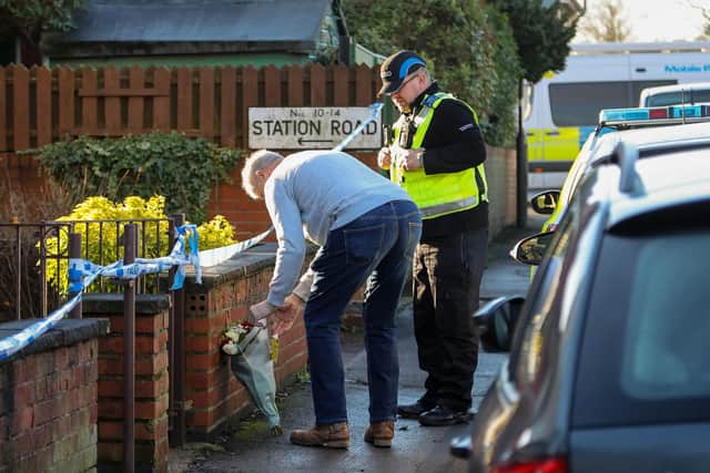 A man leaves flowers near the crime scene in Station Road