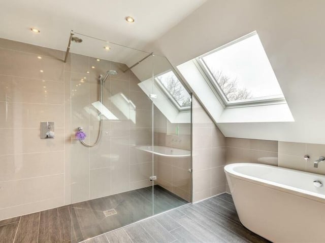 Completing our tour of the interior of the house is this family bathroom/wet room. It consists of a large bathtub, separate walk-in double shower enclosure with rainfall shower, wall-hung wash hand basin with recessed, tiled shelving above, and a wall-hung low-flush WC. Other features include eight ceiling spotlights and a Velux window.