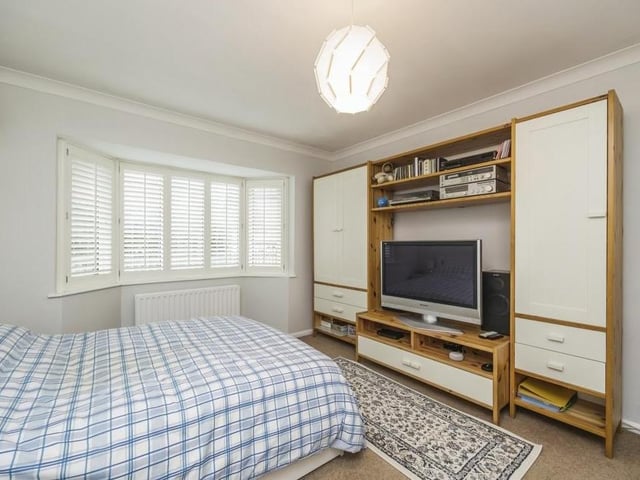 The second bedroom has a big, double-glazed bay window facing the front of the bungalow. The floor is carpeted, and there is ample space for storage.