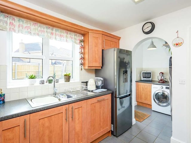 A second shot of the kitchen where, as you can see, an archway leads to a useful utility room, which has space and plumbing for a washing machine. The floors of both the kitchen and the utility room are tiled.