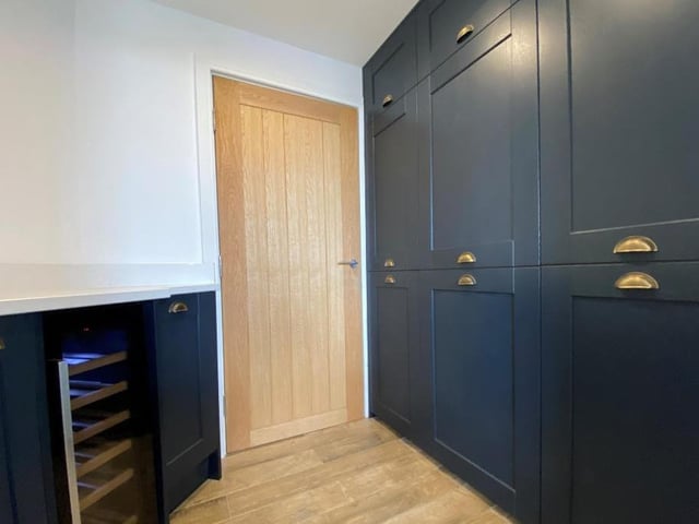 Next to the kitchen is this handy utility room, which even includes a wine fridge. With the decor matching the kitchen, it also features a range of units and a washer/dryer.