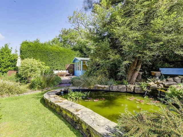 A tranquil pond forms a peaceful focal point, and a weeping tree gently softens the garden’s borders and a lovely summer house.