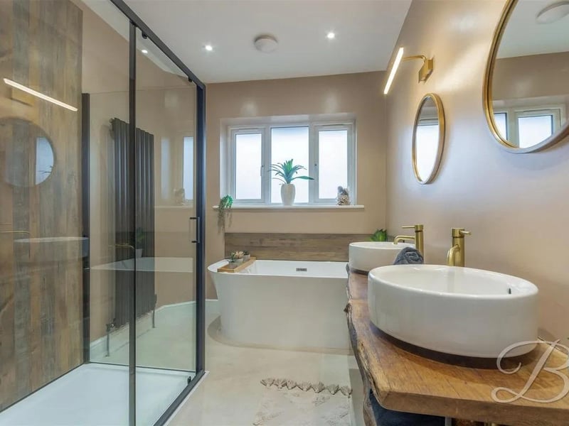 Complete with a freestanding bath, separate walk-in shower cubicle, low flush WC, twin hand wash basin, vertical central heating radiator, downlights, and an opaque window to the rear elevation.