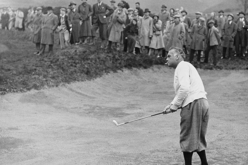 Specatators look on as Cyril Tolley, smoking a cigarette, plays a chip shot out of the sand bunker during the English Amateur Golf Championship golf tournament on 2nd May 1935 at the Notts Hollinwell Golf Club in Kirkby.