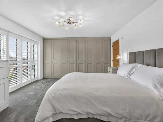 A large master bedroom with extensive fitted wardrobes across one wall, perfect for storage