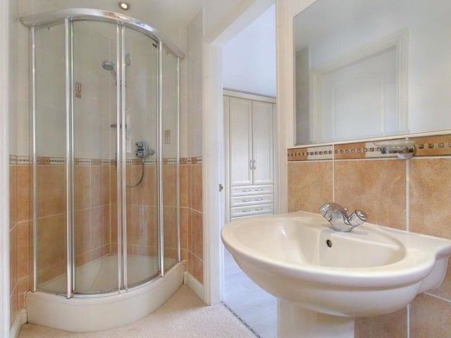 Here is the Jack and Jill shower room, which serves both the second and third bedrooms. It offers a wash hand basin, plus walk-in quadrant shower cubicle with white fittings and attractive wall tiles.