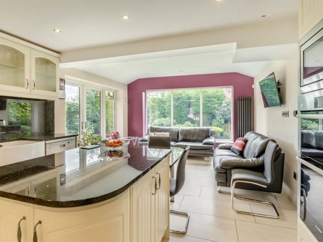 Moving on now to the open-plan dining kitchen and living area, which benefits from a recent extension. It includes an island with matching base units, an integrated wine-cooler and a fitted granite breakfast table.