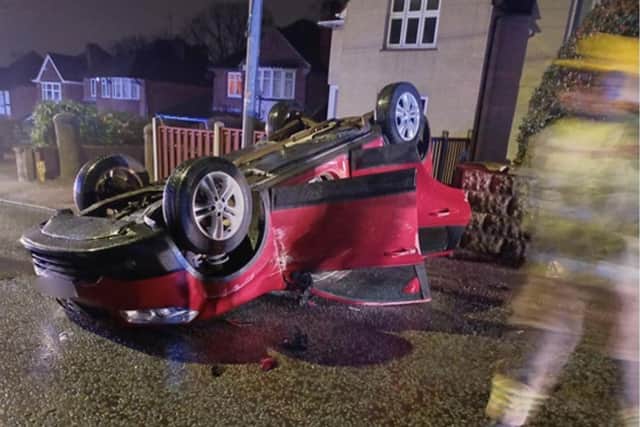 A red Nissan Quasqai collided with a parked car before rolling onto its roof