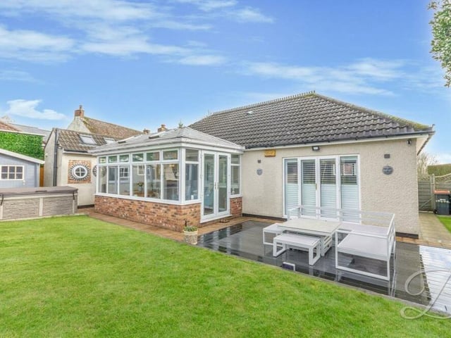 This photo shows how French doors from the ,living room lead outside to a seating area in the back garden.