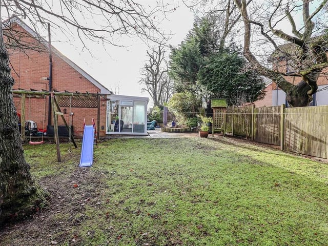 To the rear is a lawned garden with a mature Oak tree, enclosed with a fenced perimeter.