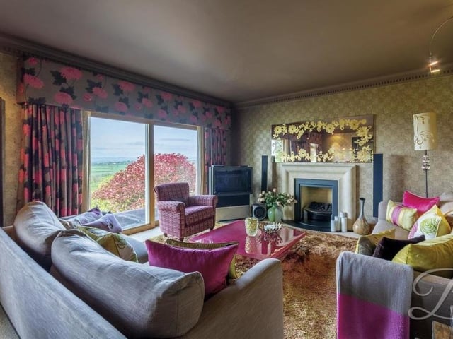 Let's launch our tour on the ground floor, where the highlight is this gorgeous, spacious lounge. A feature fireplace with surround stands out, as well as sliding glass doors that open out on to the back of the bungalow. Bespoke oak window frames, skirting boards and architraves add to the appeal of the room.