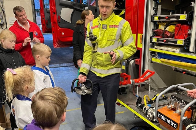 Children learn about some of the equipment carried on a fire engine.