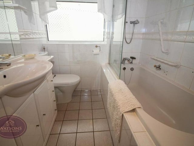 The family bathroom is a three-piece suite in white, comprising a bath with shower over, vanity sink unit, WC and heated towel-rail.