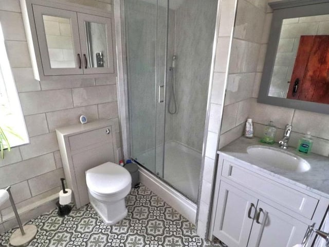 The shower room on the first floor is both modern and stylish. It has been recently fitted with a double shower, with rain-shower head and additional shower attachment, and there is also a sink with marble top and built-in vanity cupboard. A white WC is surrounded by a matching wall-mounted cabinet, while the floor is tiled.