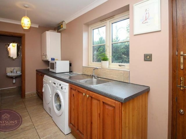 Just off the dining kitchen is this utility room, where there is space and plumbing for a washing machine and tumble dryer. A range of base units incorporates a stainless steel sink and drainer unit, while the room also houses a wall-mounted boiler.