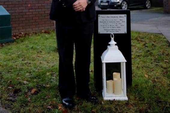 A lantern full of candles has been lit and placed alongside a memorial plaque in the grounds of the police force’s headquarters