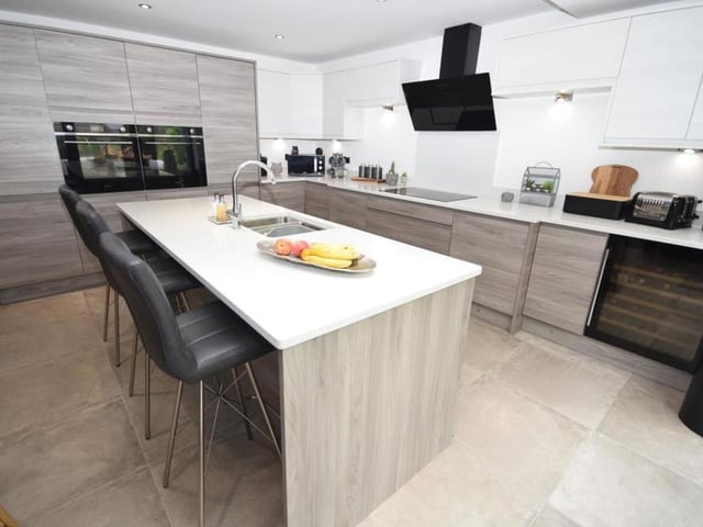 Our last look at the open-plan kitchen, which is fitted with bespoke wall and base units and on-trend tiled flooring. The sleek granite worktops are another eyecatching feature, while next to the kitchen is a utility room, with storage, sink and plumbing for a washing machine.