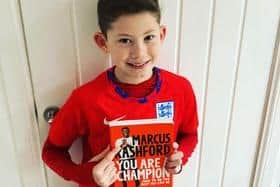 Hollywell Primary School pupil Archie holding footballer Marcus Rashford's autobiography.