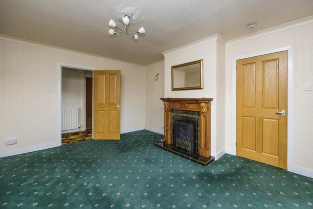 The lounge or living room is a good size and overseen by an attractive feature fireplace. The floor is carpeted, while a door leads to the kitchen.
