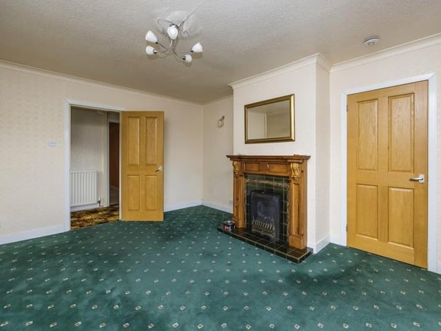 The lounge or living room is a good size and overseen by an attractive feature fireplace. The floor is carpeted, while a door leads to the kitchen.