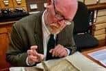 Richard Townsley studies the ancient manuscript with the first official mention of Robin Hood