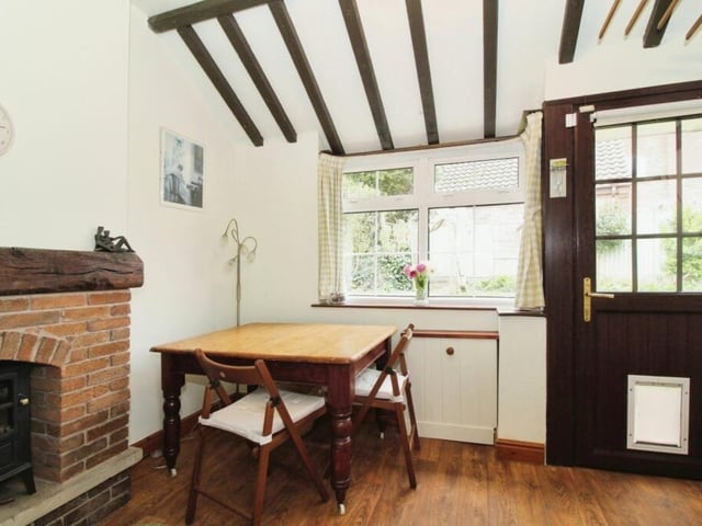Next to the kitchen is this delightful dining area, distinguished by a feature fireplace. The door is one of many entrances to the property from outside.,