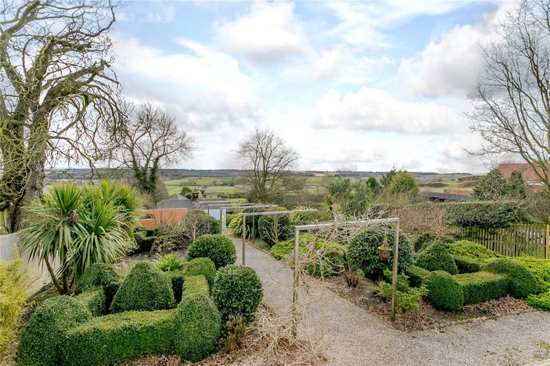 Steps lead down from the terrace to a topiary garden with a central gravelled walk way and a small lawn to the rear.