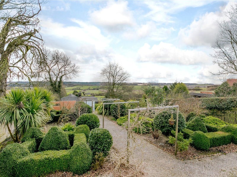 Steps lead down from the terrace to a topiary garden with a central gravelled walk way and a small lawn to the rear.
