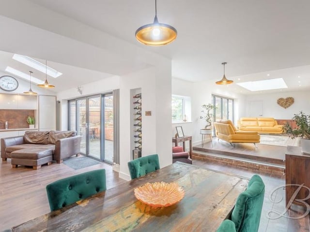 The kitchen opens effortlessly into the dining room at the £575,000 property. Oak flooring and underfloor heating add a touch of class as the space extends to the elevated sitting room to the right.