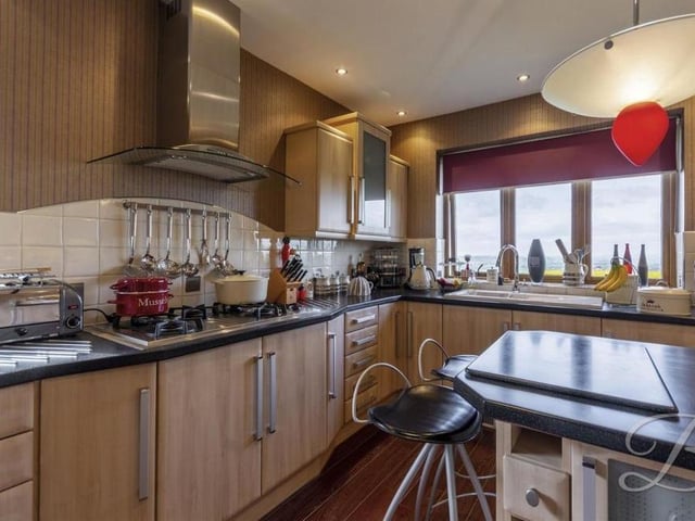 The welcoming kitchen is a commodious space, featuring matching wall and base units, worktops, a breakfast bar, hob with extractor fan above and blinded, double-glazed windows to the front and side of the bungalow.