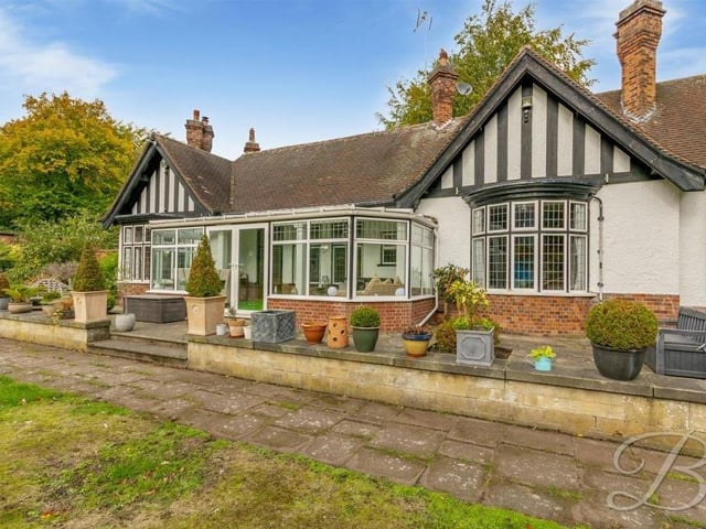 The back of the property has  a delightful, olde-worlde look to it, with the conservatory and a patio in the foreground.