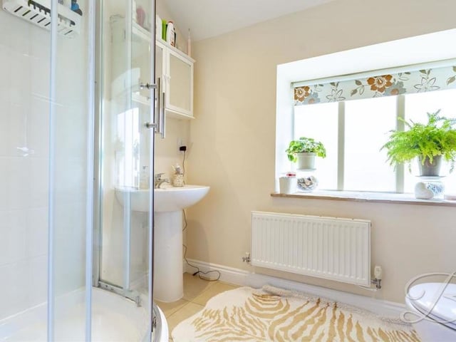 The en suite to the master bedroom consists of an enclosed shower, pedestal sink, cupboard space, low-flush WC and tiled floor.