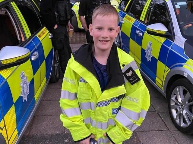 A youngster tries a police jacket for size.