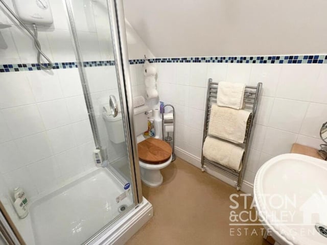 The second bedroom on the upper floor of the Mansfield Woodhouse property has access to this en suite shower room. It consists of a shower cubicle with electric shower, pedestal sink, low-flush WC, heated towel-rail and part-tiled walls.