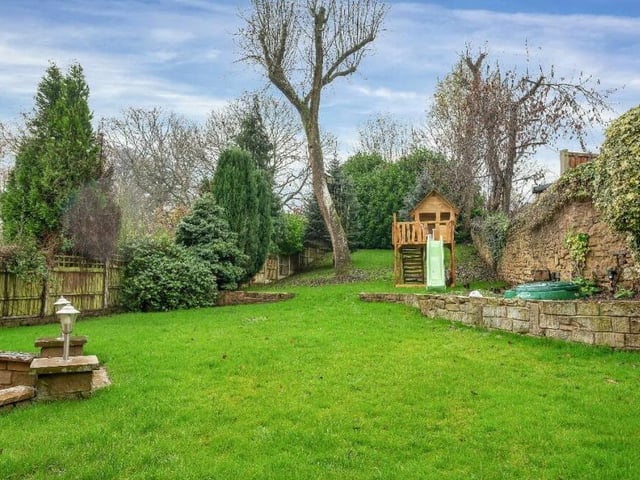 The back garden at the £585,000 property is private and enclosed. It embraces a large lawn that slowly elevates towards a high-hedged backdrop with a pleasant selection of established trees.
