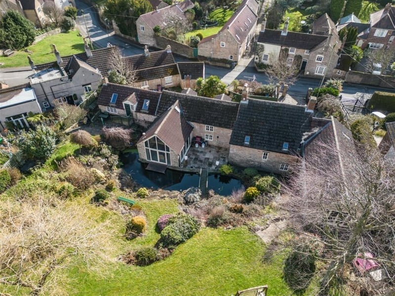 We conclude our photo gallery with two terrific shots from the air. This first one shows how the pond flows alongside the property and the bridge links a patio and the rising garden.