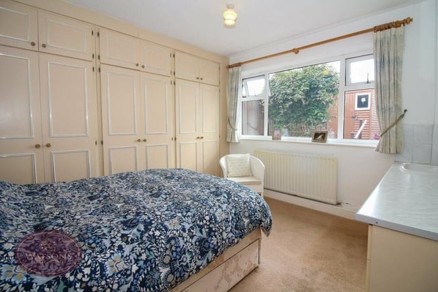 The first of the bedrooms at the Little Lane bungalow includes a range of fitted wardrobes and a vanity sink unit. The window overlooks the back of the property.
