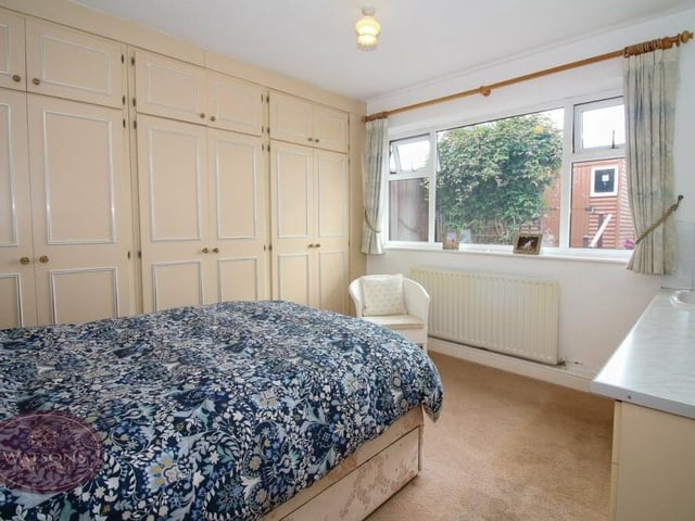 The first of the bedrooms at the Little Lane bungalow includes a range of fitted wardrobes and a vanity sink unit. The window overlooks the back of the property.