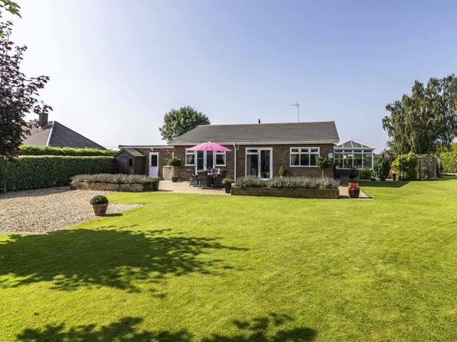 Here is a view of the £675,000 bungalow from the rear garden, with its sweeping lawn and the conservatory off to the right.