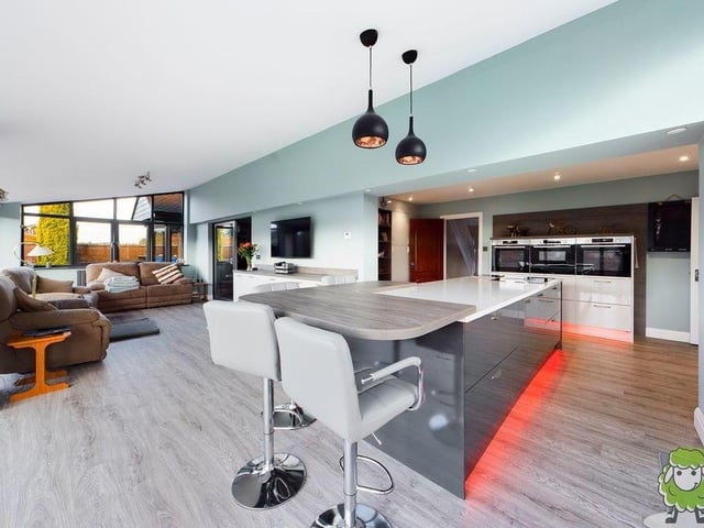 Let's start our tour of the Mansfield Woodhouse gem in this modern, open-plan kitchen, which is brand new. It is fitted with a range of glossy units, premium, integrated appliances and a breakfast bar. It also contains a comfortable living area.