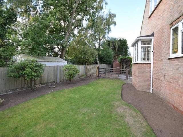 The lawn wraps itself around the house, with a gateway access to the rear. Trees and mature shrubs on the edges of the plot, and a fenced border, add to the air of privacy.