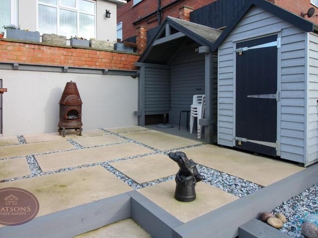This patio sits next to a timber-built shed and covered seating area at one end of the back garden.