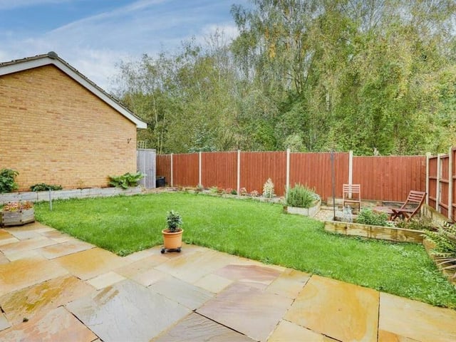 The back garden features a pleasant patio area and also a lawn with planted borders.