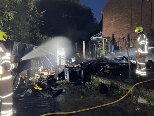 Crews pouring water on the burnt-out shed.